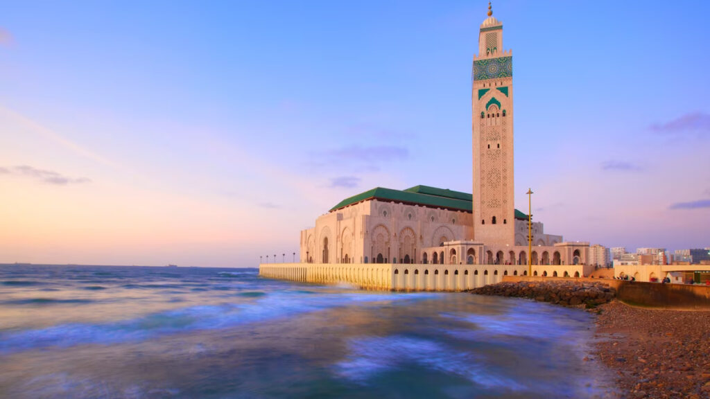 Hassan II Mosque in Casablanca with its towering minaret beside the Atlantic Ocean at dusk