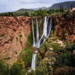 Scenic view of Ouzoud Waterfalls with lush greenery and red cliffs
