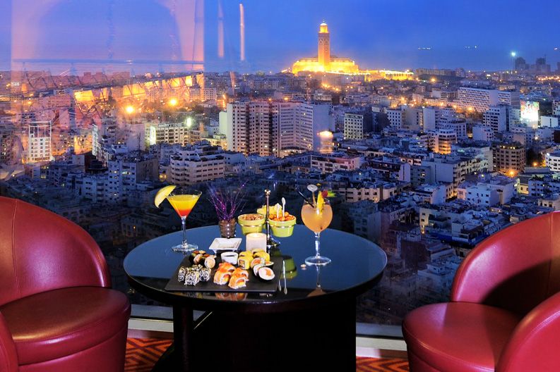 Night view of Casablanca from a rooftop bar with drinks and sushi